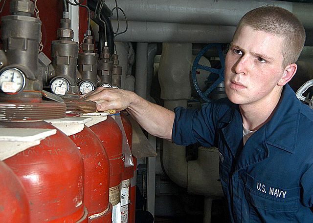 File:US Navy 030515-N-1512S-040 Machinist^rsquo,s Mate 3rd Class Daniel Griffin wipes down Halon 1301 bottles in the aft main machinery room aboard the amphibious assault ship USS Kearsarge (LHD 3).jpg